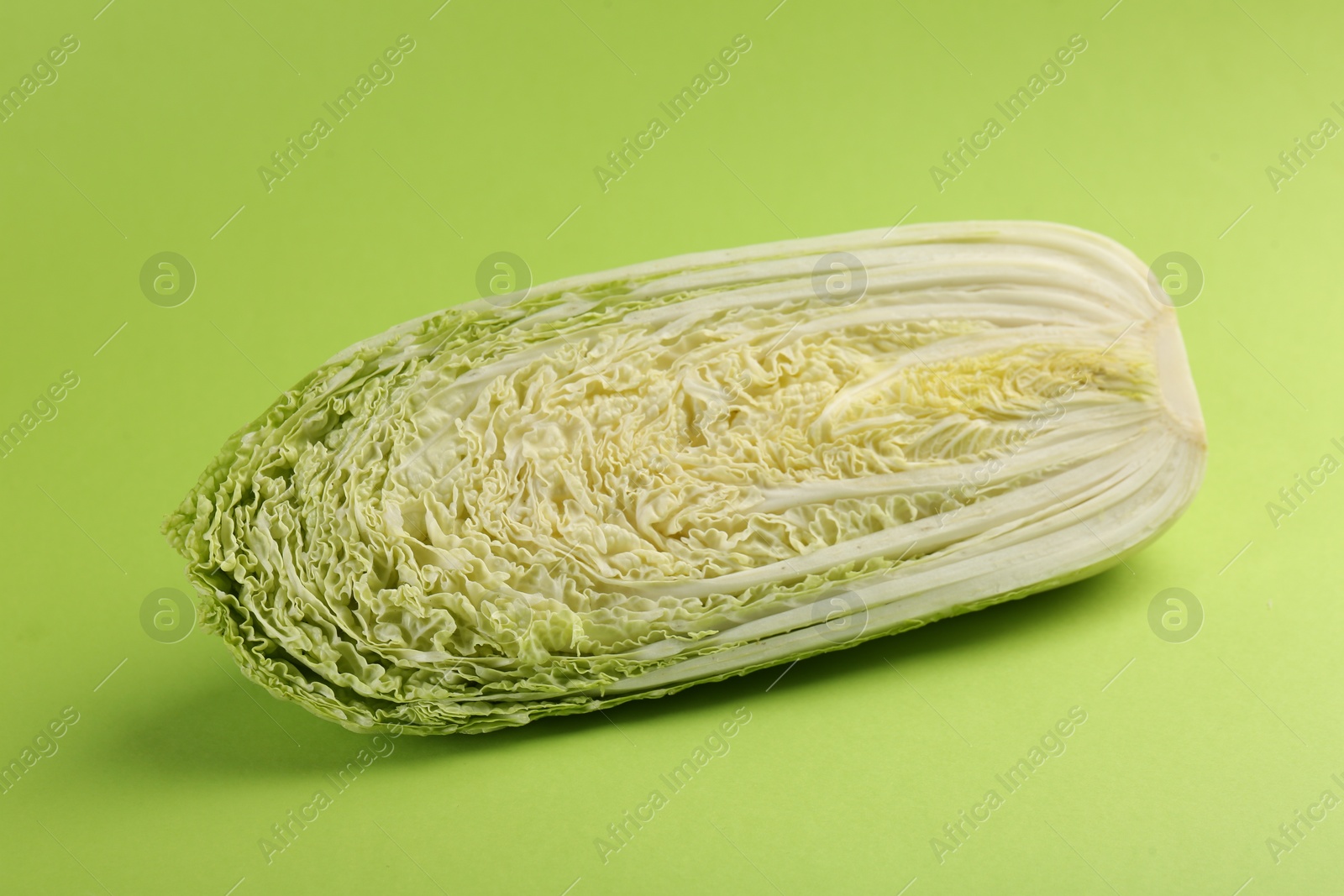 Photo of Half of fresh Chinese cabbage on light green background