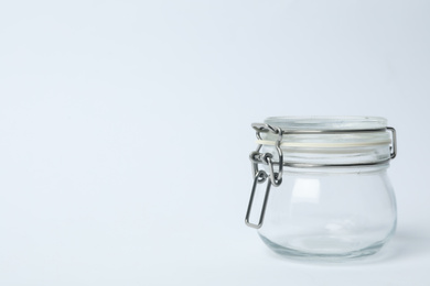 Photo of Closed empty glass jar on light background, space for text