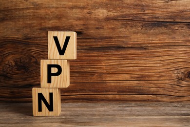 Photo of Cubes with acronym VPN on wooden table, space for text