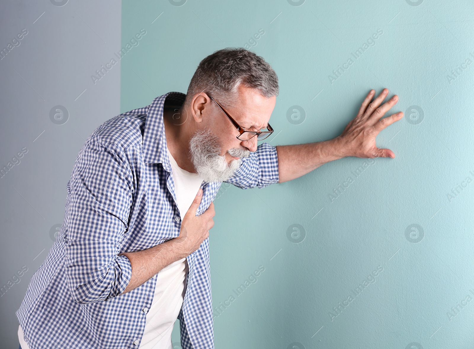 Photo of Mature man having heart attack on color background