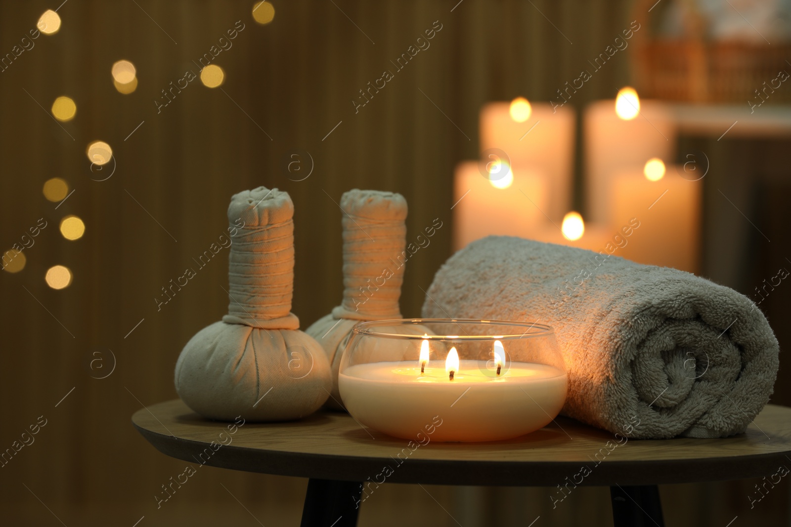 Photo of Spa composition. Herbal bags, towel and burning candle on wooden table