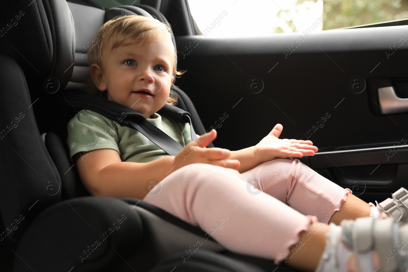 Photo of Cute little girl sitting in child safety seat inside car