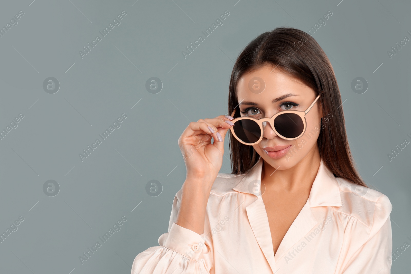 Photo of Beautiful young woman wearing sunglasses on grey background. Space for text