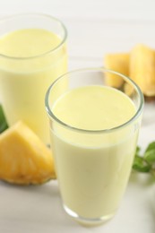 Photo of Tasty pineapple smoothie on white table, closeup