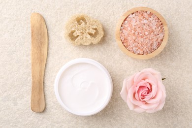 Flat lay composition with moisturizing cream in open jar and other body care products on light textured table