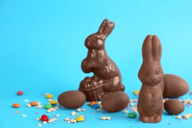 Photo of Chocolate Easter bunnies, eggs and candies on light blue background. Space for text