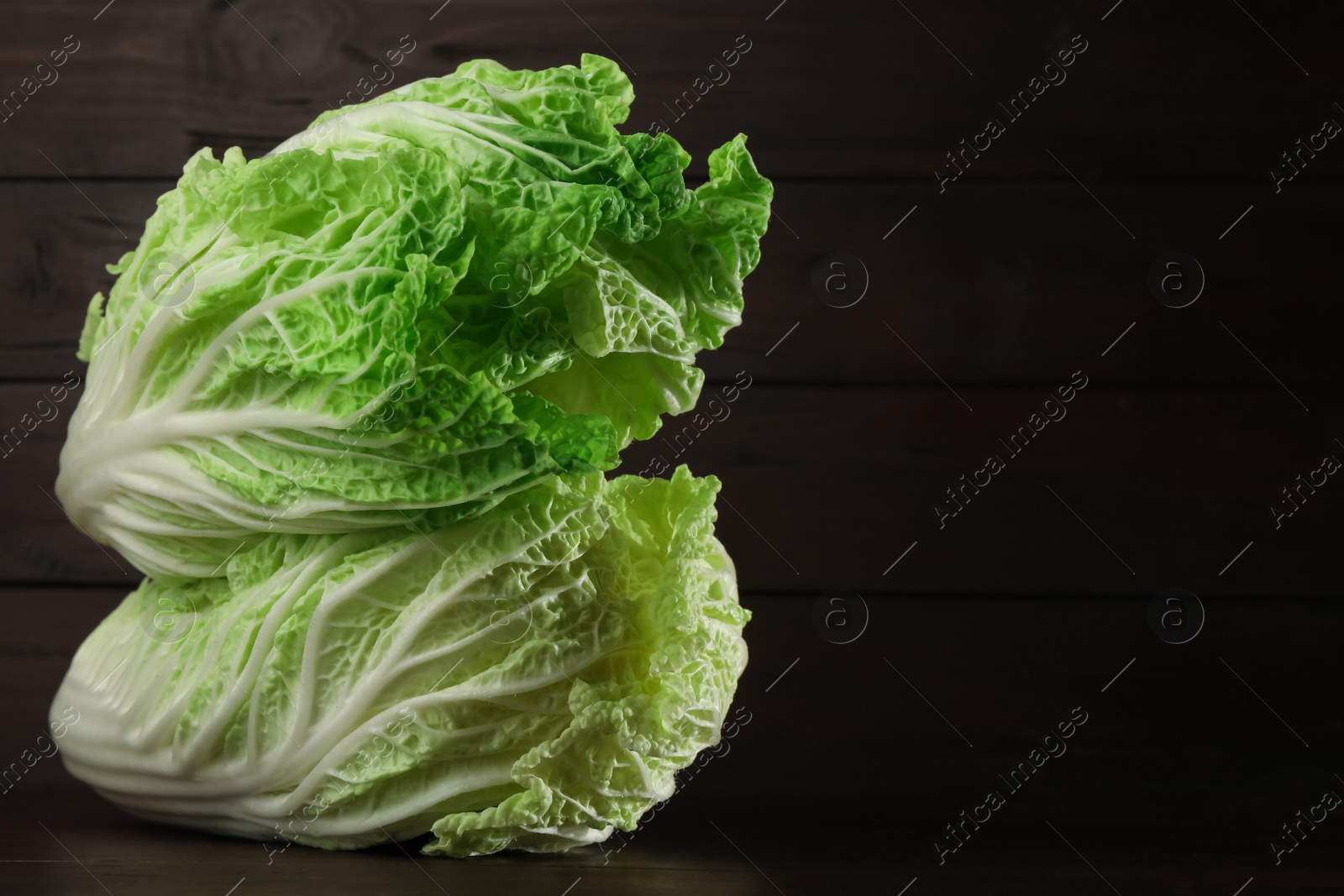 Photo of Fresh ripe Chinese cabbages on table against wooden background. Space for text