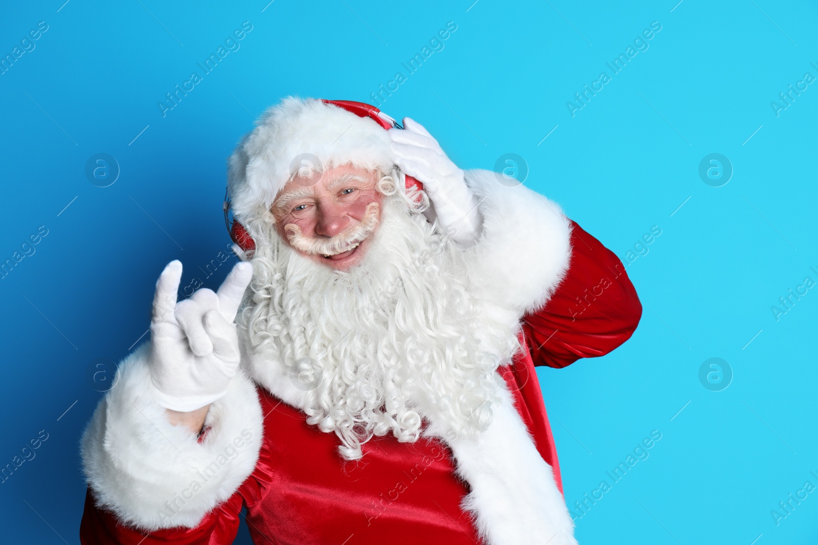 Photo of Authentic Santa Claus listening to music on color background