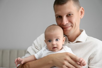 Happy father holding his cute baby at home, space for text