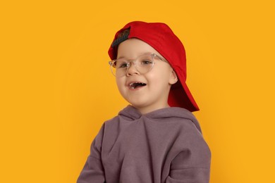 Photo of Cute little boy in glasses on orange background