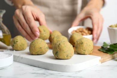 Photo of Woman making falafel balls at white marble table, closeup