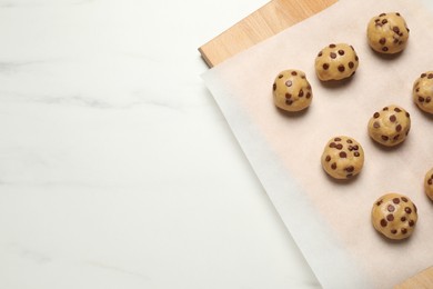 Uncooked chocolate chip cookies on white marble table, top view. Space for text