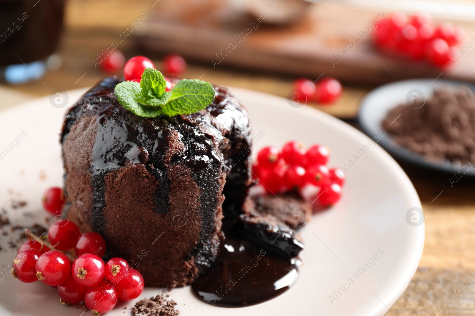 Photo of Delicious warm chocolate lava cake with mint and berries on plate, closeup