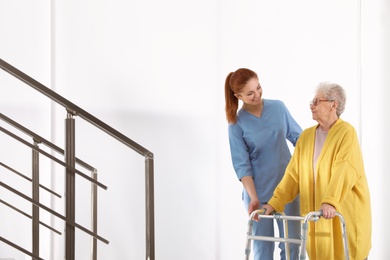 Nurse assisting senior woman with walker in hospital