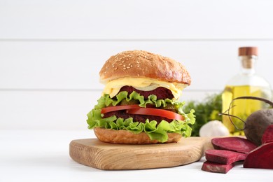 Photo of Delicious vegetarian burger and ingredients on white wooden table