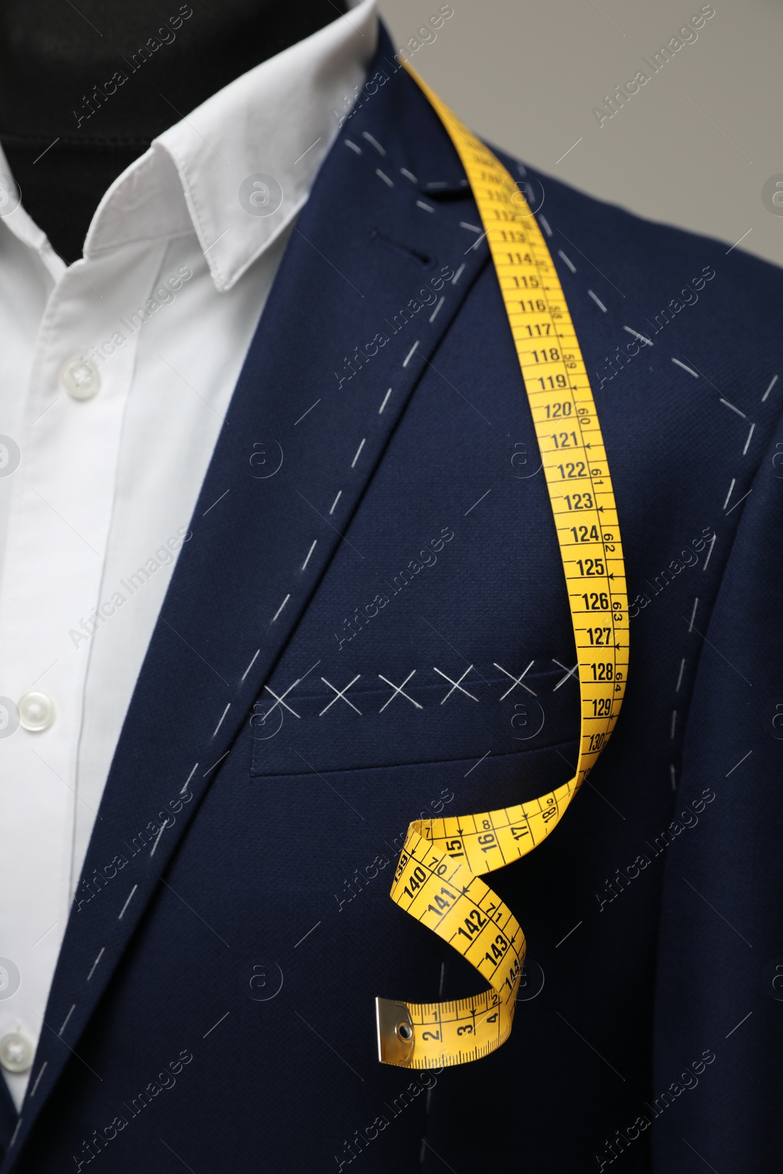 Photo of Semi-ready jacket with tailor's measuring tape on mannequin, closeup