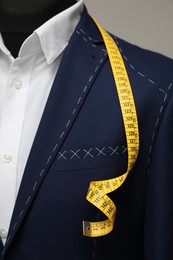 Photo of Semi-ready jacket with tailor's measuring tape on mannequin, closeup