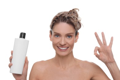 Washing hair. Portrait of beautiful happy woman with bottle showing ok gesture on white background