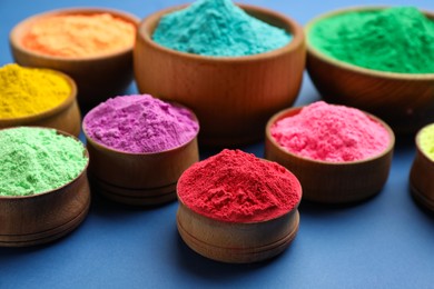 Photo of Colorful powders in wooden bowls on blue background. Holi festival celebration