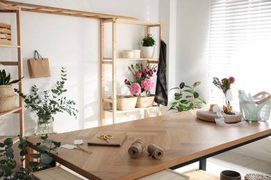 Photo of Florist's workplace with fresh flowers and wooden table