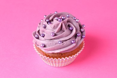 Photo of Delicious cupcake with bright cream and sprinkles on pink background