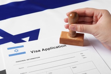 Immigration to Israel. Woman stamping visa application form on flag, closeup