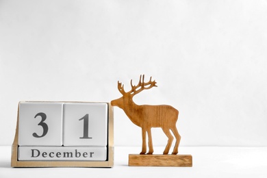 Photo of Wooden block calendar and reindeer figure on light background. Christmas countdown