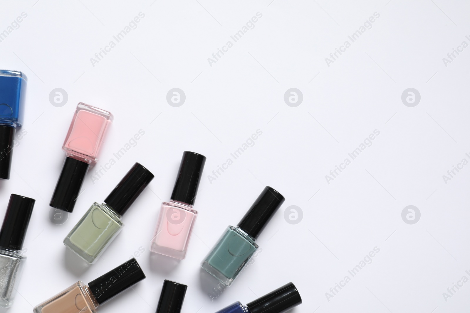 Photo of Nail polishes on white background, flat lay. Space for text