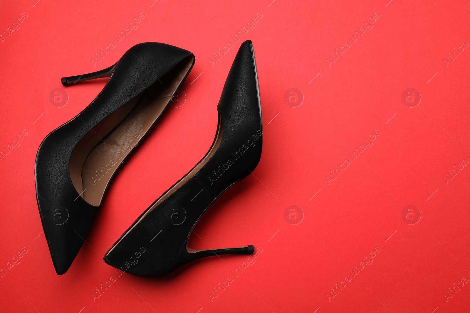 Photo of Pair of elegant black high heel shoes on red background, flat lay. Space for text