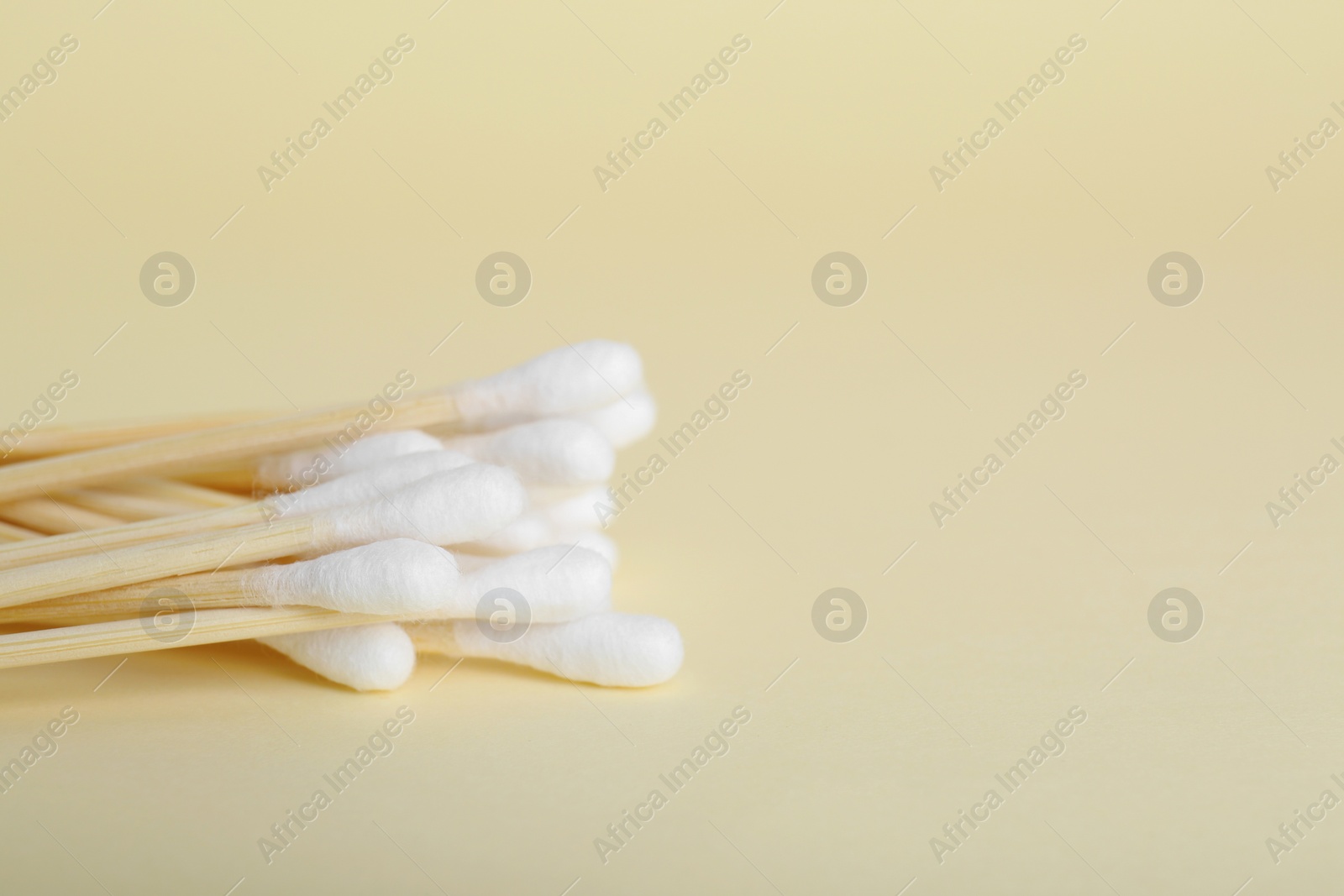 Photo of Wooden cotton buds on beige background, closeup. Space for text