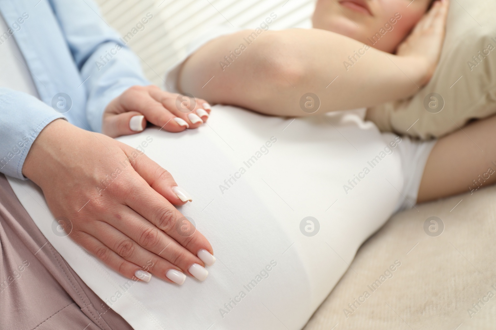 Photo of Doula taking care of pregnant woman indoors, closeup. Preparation for child birth