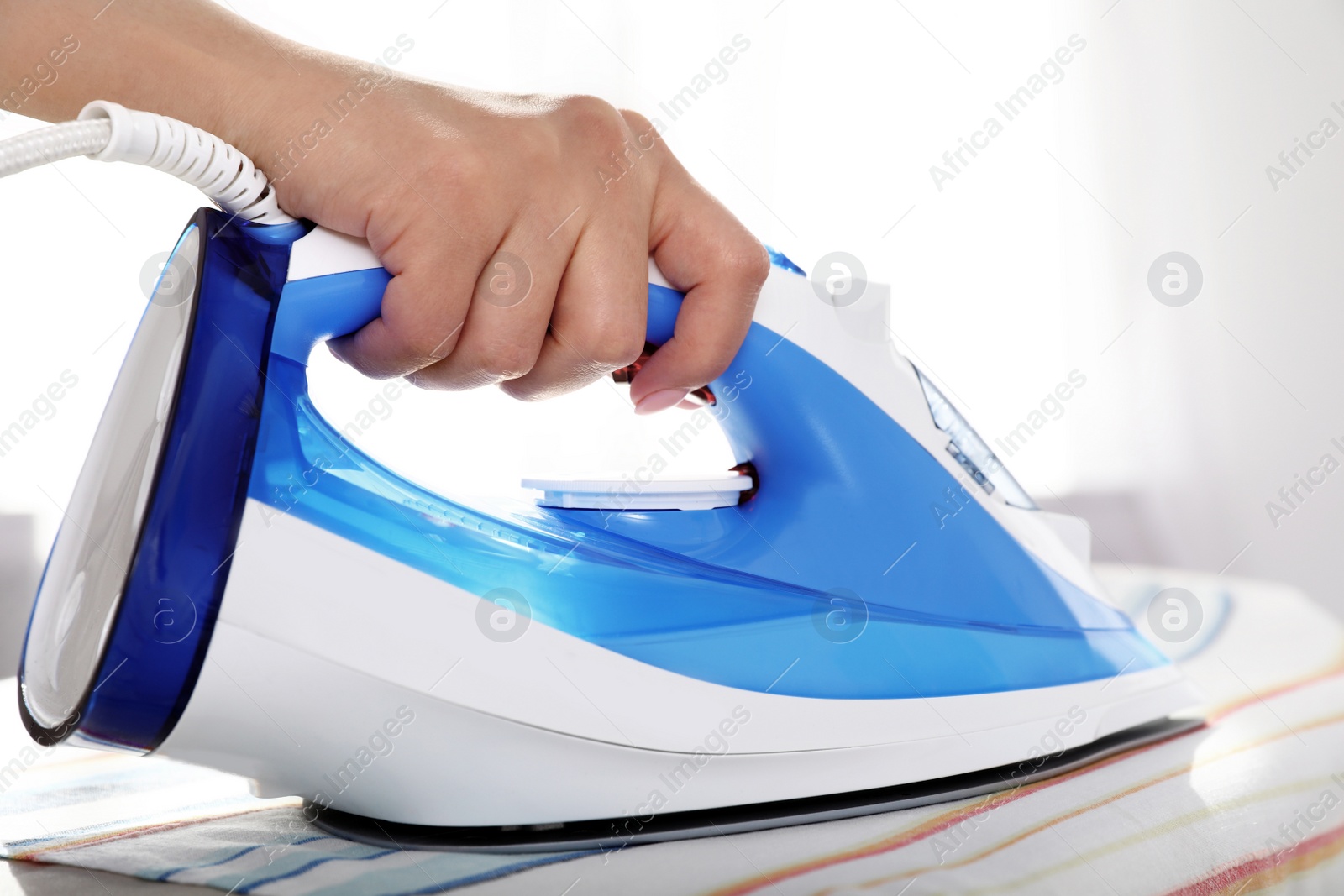 Photo of Woman ironing clothes on board indoors. Household chores