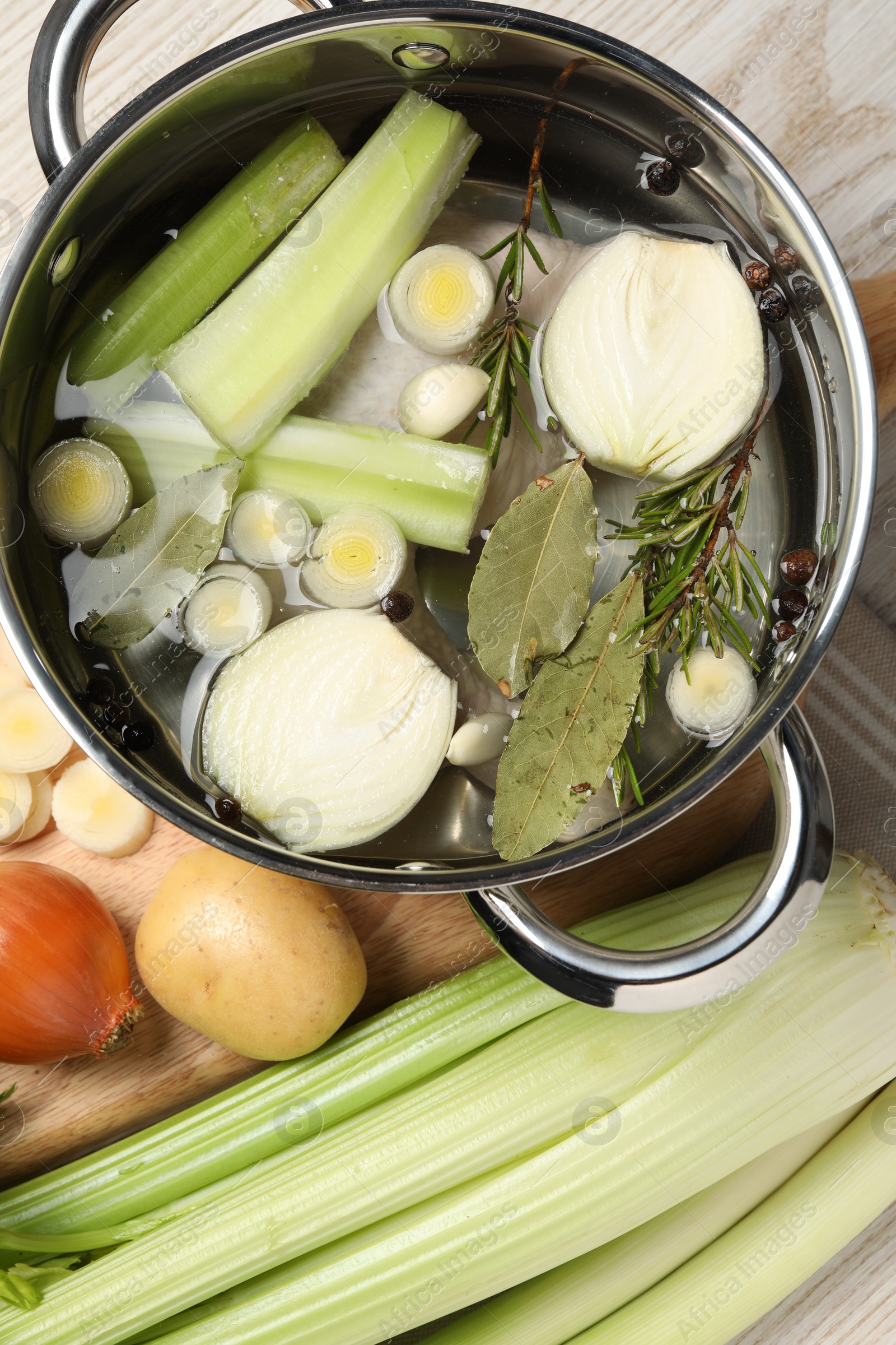 Photo of Pot and different ingredients for cooking tasty bouillon on white wooden table, flat lay