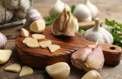Photo of Fresh sliced and whole garlic on wooden table, closeup. Organic product