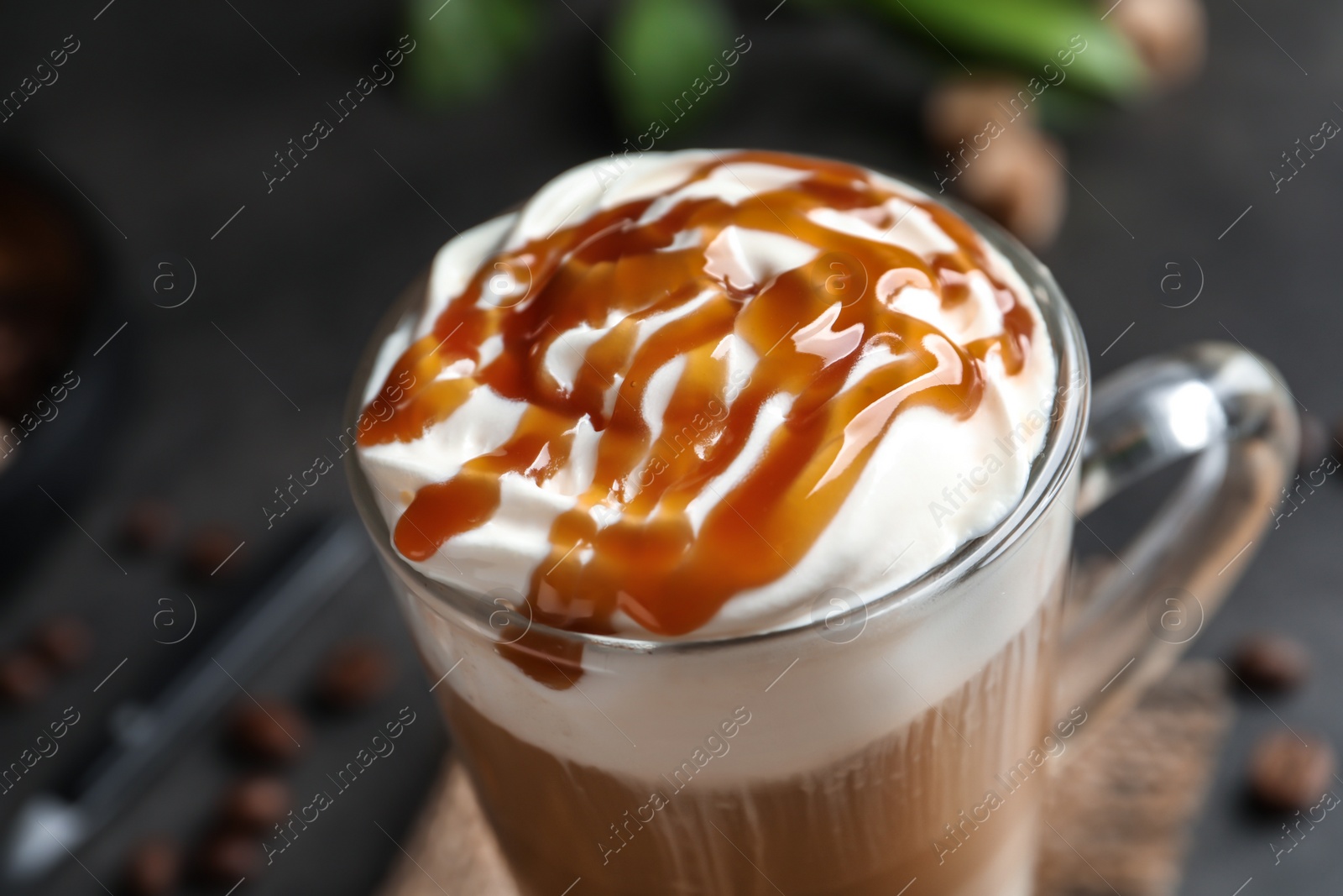 Photo of Glass cup with delicious caramel frappe on table, closeup