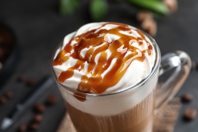 Photo of Glass cup with delicious caramel frappe on table, closeup