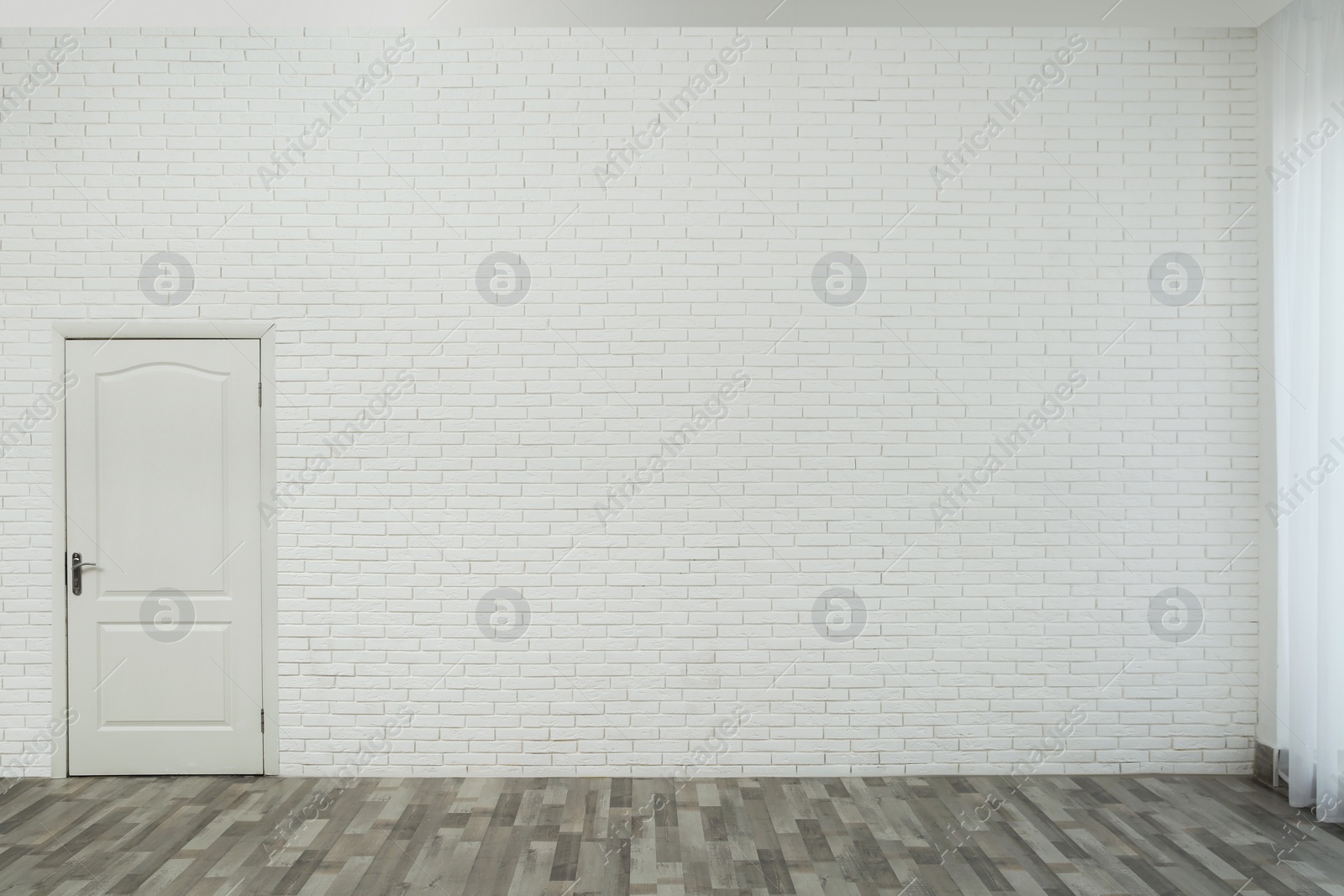 Photo of Empty room with brick wall, white door and laminated floor