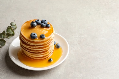 Photo of Plate with pancakes and berries on grey background