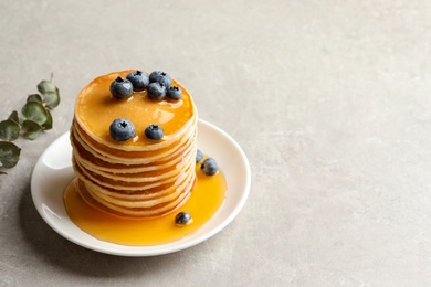 Plate with pancakes and berries on grey background