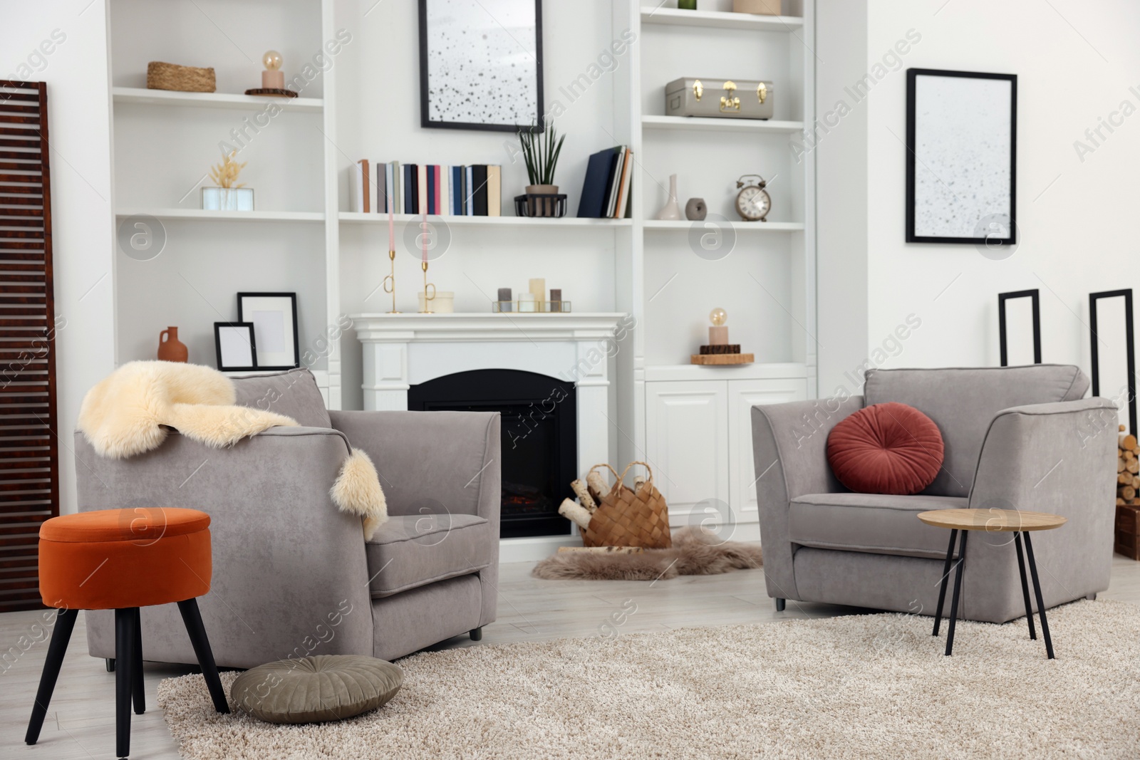 Photo of Comfortable armchairs, fireplace and shelves in living room. Interior design