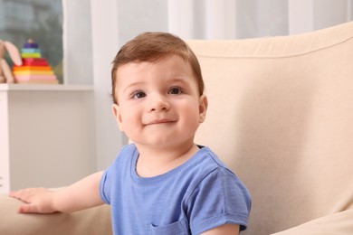 Photo of Cute baby boy sitting in armchair at home