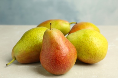 Photo of Heap of ripe juicy pears on light stone table against blue background