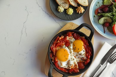 Tasty Shakshouka served on white marble table, flat lay. Space for text
