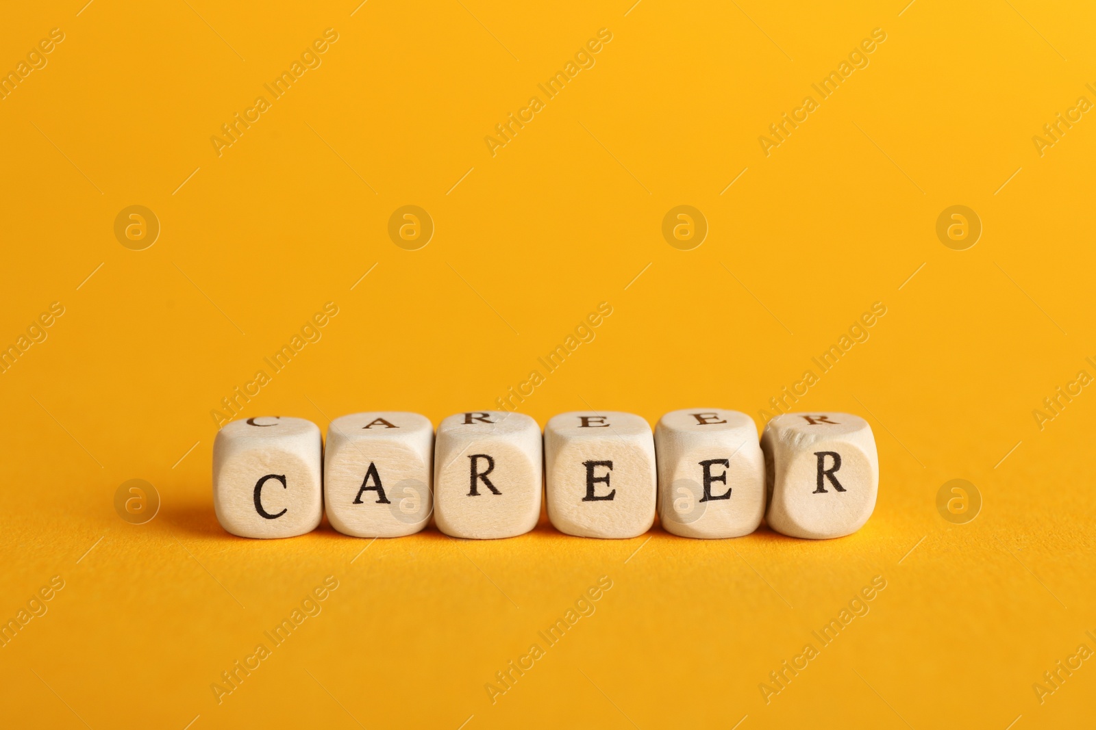 Photo of Stone cubes with word CAREER on orange background. Space for text