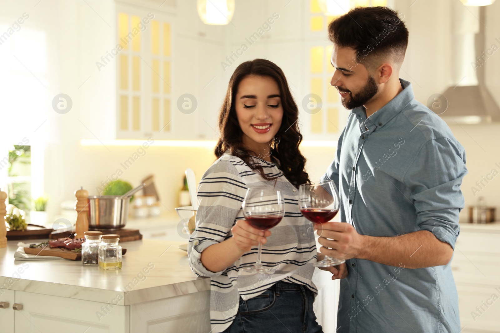 Photo of Lovely young couple drinking wine while cooking together at kitchen