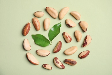 Flat lay composition with Brazil nuts and leaves on color background