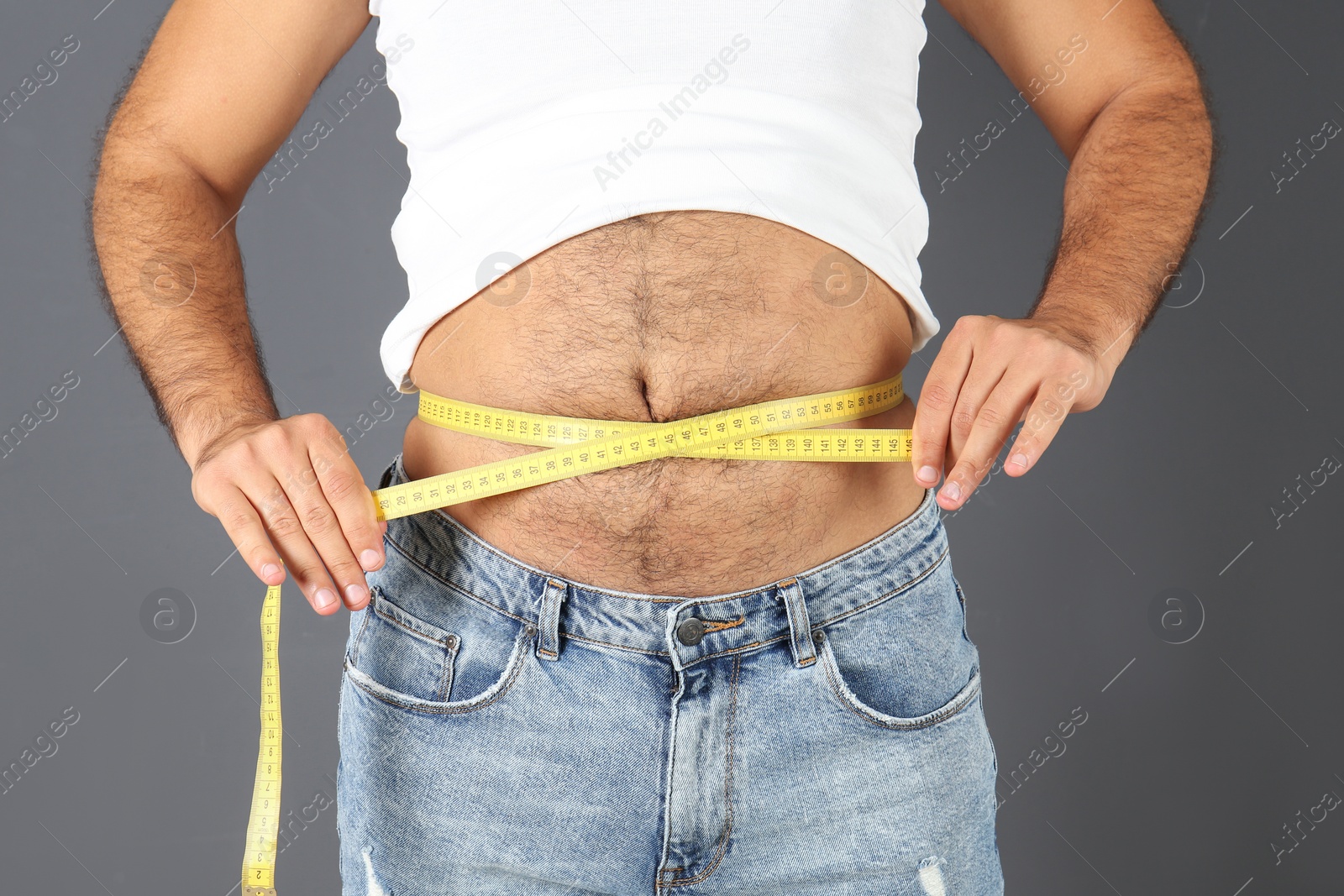 Photo of Overweight man with measuring tape on gray background, closeup