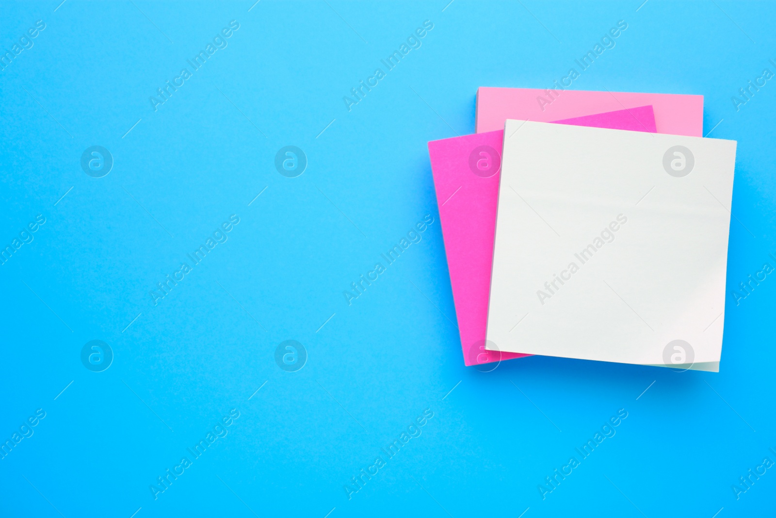 Photo of Paper notes on light blue background, top view. Space for text