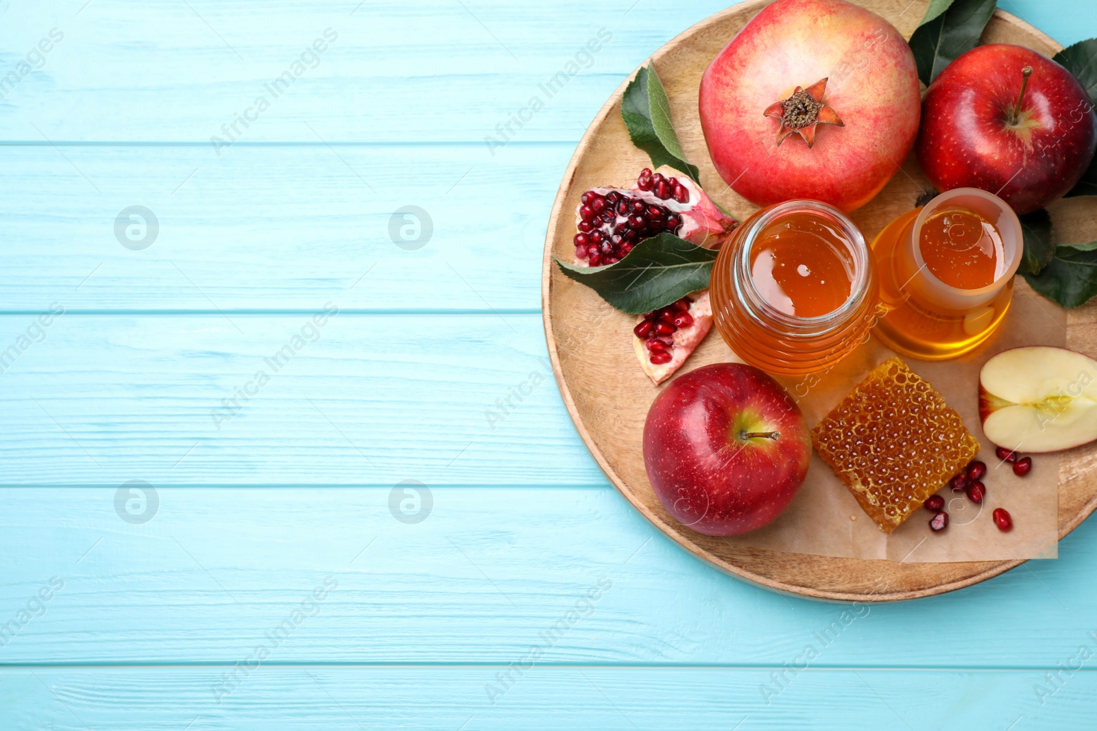 Photo of Top view of honey, apples and pomegranates on light blue wooden table, space for text. Rosh Hashanah holiday