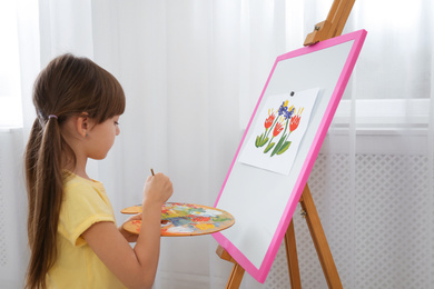 Cute little child painting during lesson in room